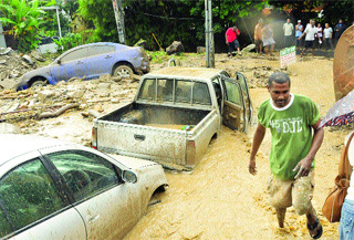 Vehicles, rocks and debris block the roadway yesterday after heavy rains sent torrents of muddy water through Saddle Road, Maraval. These three vehicles were pushed several feet away by flood waters.  (Trinidad Express photo)