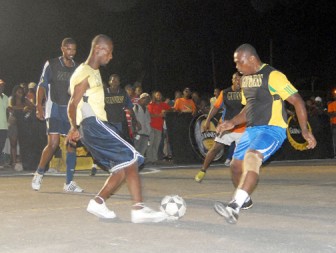 Two players tussle for possession during action in the Guinness-in-the-Streets tournament at the National Cultural Center tarmac  Tuesday evening. (Orlando Charles photo)