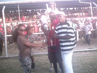 Port Mourant Turf Club (PMTC) representative Compton Sancho presents the Winning I class trophy to Lisa Gopaul of the Crawford Racing Stable. 