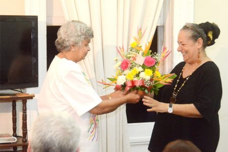 Doreen de Caires (left), wife of the late David de Caires, presents a bouquet of flowers to Vanda Radzik, the Chairman of the Board of Directors for Moray House Trust. 