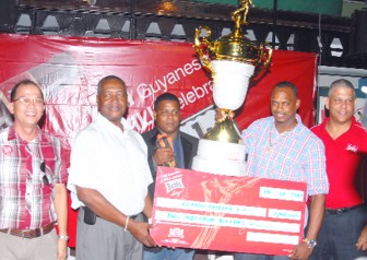  Assistant Managing Director of Banks DIH Limited Mr. George Mc Donald, second left, hands over the first place trophy and cheque to Alpha United skipper Howard Lowe. (Orlando Charles photo)
