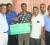 Supervisor of the Electrical Department of Hadi’s, Dionne Johnson, third from left, presents the sponsorship cheque to an official of the Guyana Floodlights Softball Cricket Association.
