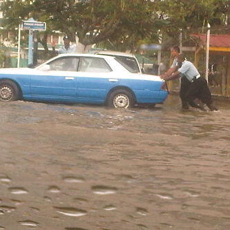 These policemen had to push this vehicle through deep waters in Eve Leary yesterday. (Treiston Joseph photo)