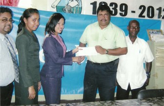 Treasurers of the Berbice Cricket Board Anil Beharry receives the sponsorship cheque from Tiffany Asregado of Republic Bank (Guyana) Limited while other bank staffers look on.