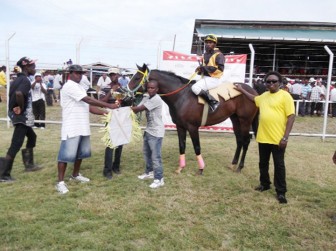 A representative of the Port Mourant Turf Club presents the Laljit Trophy to Paul Delph of the Elcock stable for the victory by Celebration Time in the `G’ class event.