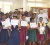 Region 10 Literacy Coordinator Ava Chapman (first, left) and Peace Corps Volunteer Timothy Tibbs (third, right, second row) smile proudly as several primary and secondary school student participants in the Regional Authors’ Fair display their certificates. 