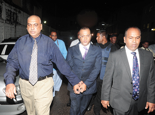 Ian Alleyne (centre) being escorted by a policemen (left) and his attorney (Trinidad Express photo)