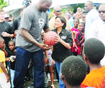 Former  NBA star, Shaquille O’Neal (left), the face of Government’s “Hoop of Life” basketball competition, teams up with Prime Minister Kamla Persad-Bissessar on the court at Beetham Gardens on Saturday, giving her a lift to dunk one—to the delight of the large gathering of residents on 23rd Street.
