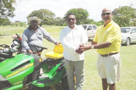 Jerome Khan (right) hands over the tractor to Kishun Bacchus while Mike Gayadin looks on. 