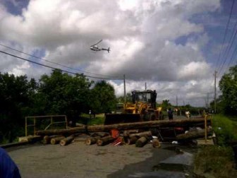 Planks being bulldozed off the bridge as an army helicopter circles.