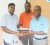 GWI Chief Executive Nigel Niles (right) hands over contracts to Suresh Jagmohan as Procurement Director Aubrey Roberts looks on.