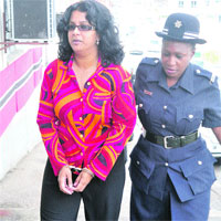 Travel agency manager Vicky Boodram is escorted to the San Fernando Magistrates' Court yesterday, after she was denied bail on fraud charges relating to boguspackages dating between 2007 and 2010. (Trinidad Express photo)