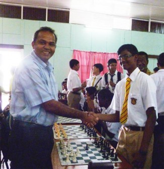 Minister of Culture, Youth and Sport Dr. Frank Anthony greets former national junior chess champion and Queen’s College board one player Cecil Cox prior  to their moving the ceremonial pieces to declare the championships. (Iva Wharton photo)