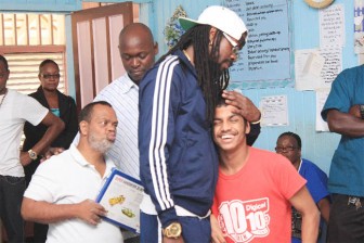 Beenie Man embracing 18-year-old Anil after his presentation while 53-year-old Rudolph (left) looks on. (Arian Browne photo)