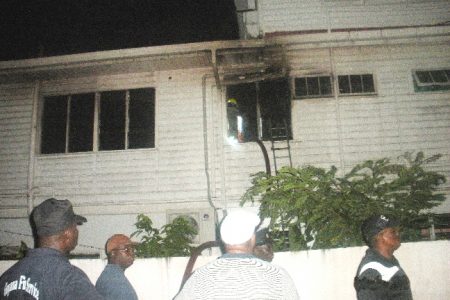 The window to the office that was broken to gain access to the building. In the compound of the building east of the ministry, firefighters watch on as Fire Chief Marlon Gentle (right ) directs his troops.