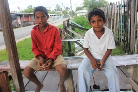 Two children relaxing under a local shop