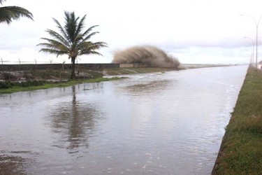 Over the wall: Another wave bursting over the seawall to continue making a river of the East Coast Demerara roadway yesterday afternoon. (Photo by Arian Browne)