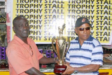 Marlon Washington (left) receives the first place trophy for the upcoming Premium Beer Futsal Classic tournament on behalf of Unique Entertainment yesterday from a representative of the Trophy Stall. (Orlando Charles photo)
