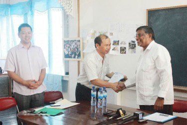 President of the Chinese Association Shilong Chow (centre) thanks Minister of Labour Nanda Kishore Gopaul after receiving a copy of Guyana’s Labour Laws translated in Chinese.  