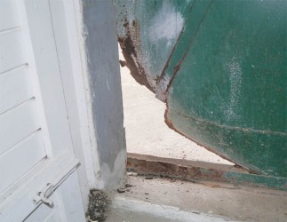 The rotten section of the metal door at the back of the market that the bandits ripped open