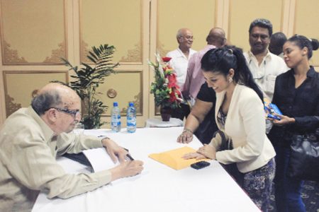 Dr Rudy Insanally autographs a book at the launch on Friday