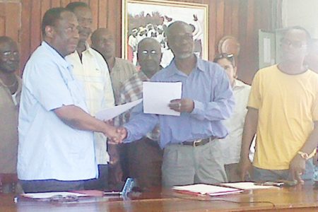GPSU President Patrick Yarde (left) and GTUC President Norris Witter (third, right) exchange copies of the signed communiqué in the presence of other trade unionists