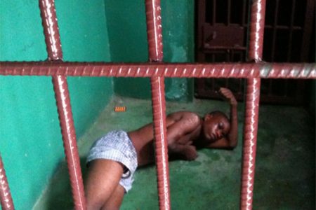 Akeem Charles lying on bare concrete floor during his detention last month. His right eye seems to be swollen. (Stabroek News file photo)
