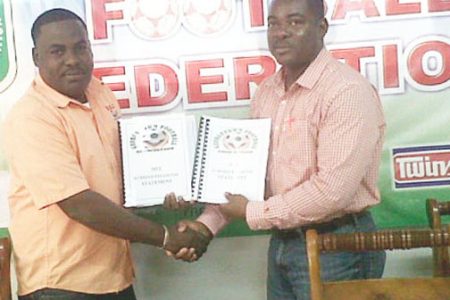 GFA’s treasure Dexter Schultz presenting the audited financial reports to acting GFF president Franklin Wilson (right).