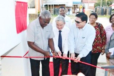 Minister Robeson Benn (left) in his capacity as acting Foreign Affairs Minister cutting the ceremonial ribbon to commission the new CCTV channel on February 9. He is assisted by China’s Ambassador to Guyana Zhang Limin (centre) and Chairman of the board of the National Communications Network, Dr Prem Misir. (GINA photo) 