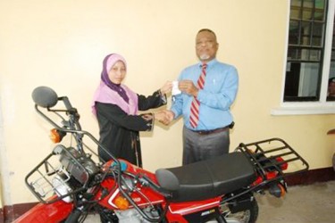 Prime Minister Sam Hinds (right) handing over the keys to the bike to Rosie George. (GINA photo)