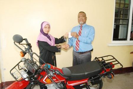 Prime Minister Sam Hinds (right) handing over the keys to the bike to Rosie George. (GINA photo)