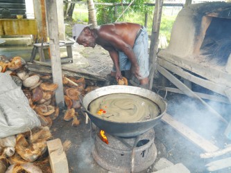 Jacob Anthony placing coconut husk in the fire to boil the casereep