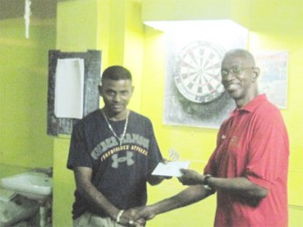 President of the Guyana Darts Association Grantley Culbard hands over the prize to Anil Lachman.