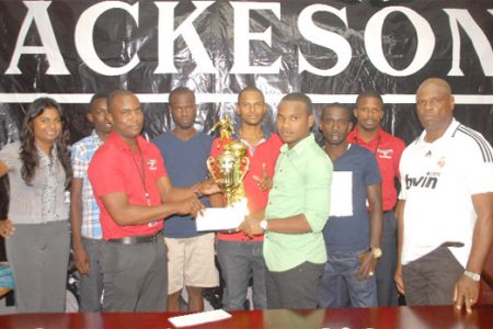 Retrieve Unknowns captain Travis Adolph (right in the foreground) collects the winning trophy and his team’s $250,000 first prize from ANSA McAl representative Jamal Douglas while other supporters look on.
