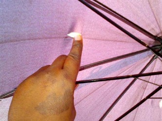 The woman points to one of the holes in the umbrella. 