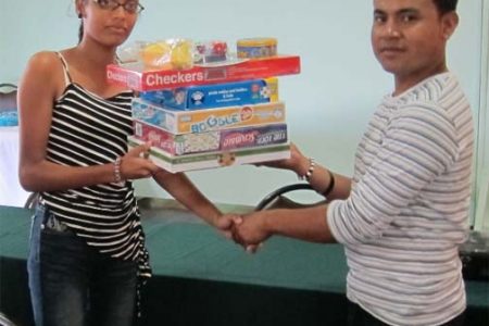 Padmanie Chattergoon (left) representative of Diamond’s student club receives a set of games from DAG Committee Member James Williams.
