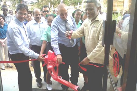 Prime Minister Samuel Hinds (right) cuts the ribbon to open the new Port Kaituma branch of GBTI assisted by its Chairman Robin Stoby, other officials and members of the community. (Photo by Mandy Thompson)