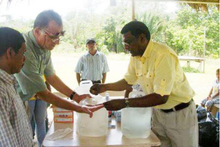 Chief Medical Officer Dr. Shamdeo Persaud (right) demonstrating how to use purification tablets to residents of Canal Bank, Region One (GINA photo)
