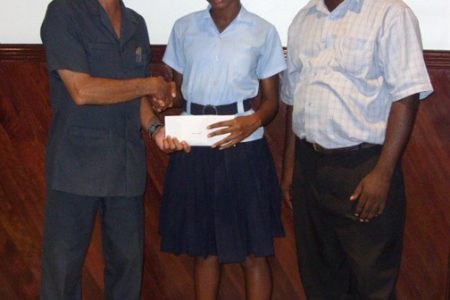  CARIFTA athlete, Tirana Mitchell receives a cheque from Ming’s Products and Services Limited Director Colin Ming in the presence of Mark Scott, coach of the CARIFTA Team at the Ming’s Products and Services Limited Kingston.