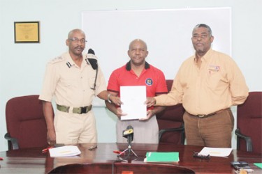 Donald Sinclair, Director of Flex Night Inc (centre) with Director of Prisons, Dale Erskine (left) and CEO of Demerara Mutual Life Assurance Society Ltd, Keith Cholmondeley holding the MOU.