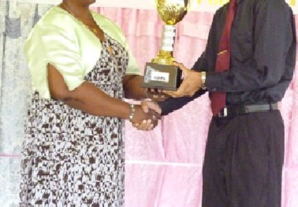 Regional Education Officer Marlyn Jones-O’Donoghue presents Region Three’s top CSEC performer Meikel Mahabir with his trophy.
