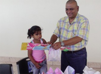 CEO of the BBCI, Omadat Samaroo handing over a kite to a child at a special event the company hosted yesterday 