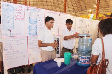 Students of the Skeldon Line Path Secondary giving the judges a demonstration on their project ‘Water filtration and purification system’