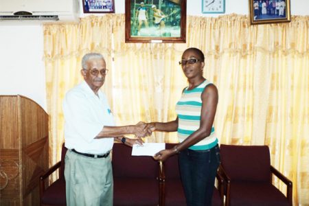 Personnel Manager of Noble House Seafoods Piercy Corlette hands over the cheque to the Athletics Association of Guyana (AAG) Secretary, Cheryl Sam yesterday afternoon at the Olympic House, High Street, Kingston.