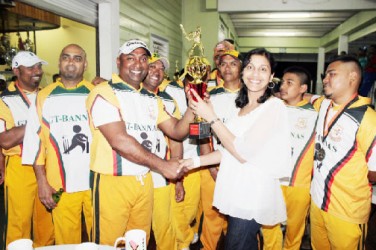 In picture, US-based Dolly Sangster hands over the trophy to captain of the winning team Mark Khan.