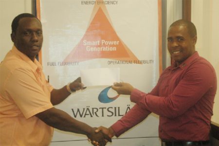 Contracts Manager at Wartsila, Arron Fraser presents Athletics Association of Guyana Vice-President Gavin Hope with the incentives for the Youth/Junior Championship on Monday at Wartsila, Kingston.