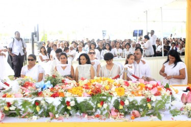 The family of Reepu Daman Persaud sitting before his doli at the International Convention Centre yesterday. His widow Indrani is at left.