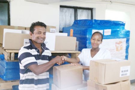 Sharir Chan, Chief Operations Officer, Guyana Medical Re-lief presents boxes of medication and supplies to a representative of the Mahaicony Hospital.