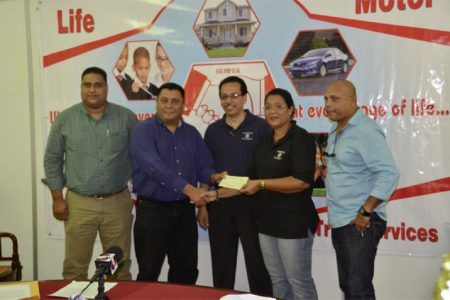 Hand-in-Hand, Human Resources and Administrative Manager, Zaida Joaquin (second right) hands over the cheque to president of the DCB, Raj Singh in the presence of other DCB officials and Director and Fire Manager of the insurance company, Howard Cox.

