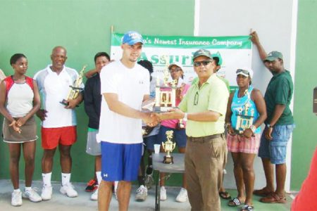Men’s singles champion Anthony Downes collects his trophy from Assuria’s Dick Wesenhager as other contestants look on.